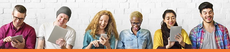 Six people standing next to each other, smiling while looking at their smartphones or tablets.