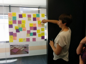 meg howie designer Designer Meg Howie pointing at post-it notes stuck to a wall.